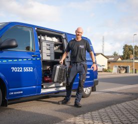 Servicetekniker foran sin bil i villakvarter