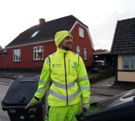 Glad mand i gult arbejdstøj med to skraldespande i hænderne