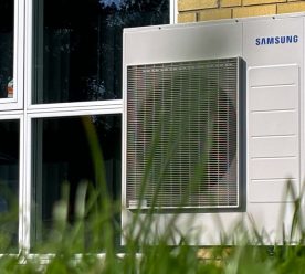 Samsung varmepumpe op ad en gul mur ved siden af vindue