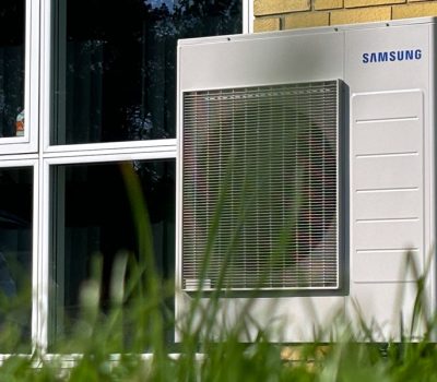 Samsung varmepumpe op ad en gul mur ved siden af vindue