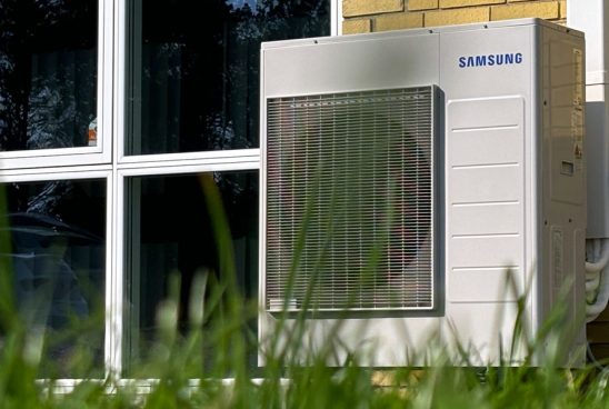 Samsung varmepumpe op ad en gul mur ved siden af vindue
